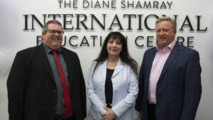 Three individuals standning in front of sign for The Diane Shamray International Education Centre